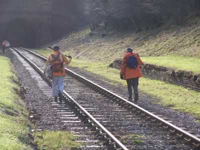 Track workers walking along track towards a tunnel