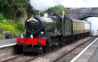 steam locomotive entering station with a passenger train