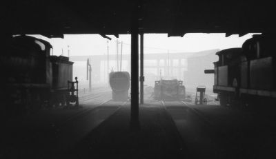 view out from inside a steam locomotive shed, with several engines present