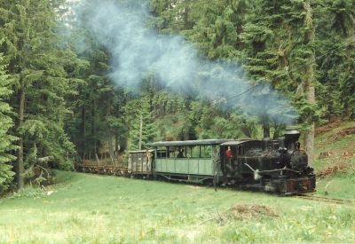 Romanian narrow gauge forestry railway – Covasna Comandău – Oliver Wileczelek – 24 June 1994. CC-by-SA-3.0. Narrow gauge steam-hauled mixed train emerging from a forest deep in Romania