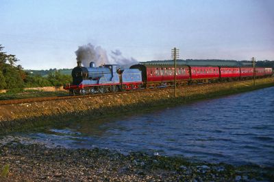 Steam-hauled passenger train on a stone causeway across an estuary