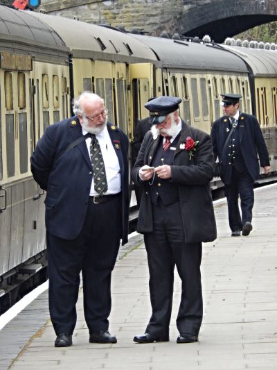 two portly be-whiskered station staff discuss the next departure at a heritage railway