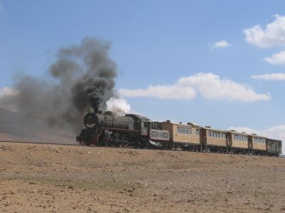 Steam-hauled passenger train crosses the desert in Jordan.