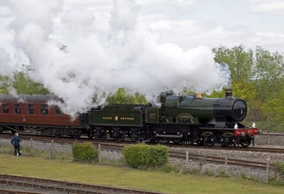 Early twentieth century GWR 4-4-0 steam locomotive 'City of Truro' hauling a passenger train at a heritage centre.