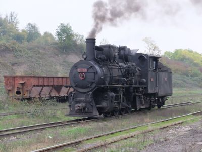 Narrow gauge 2-8-0 steam locomotive and tender in a slightly overgrown yard at a coal mine in Bosnia