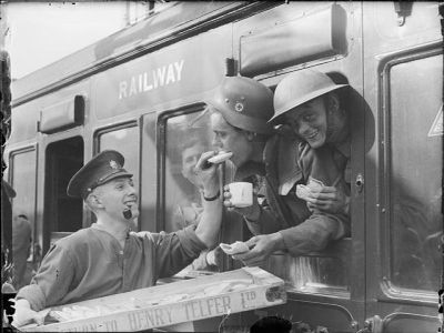 Soldiers evacuated from Dunkirk lean out of a train carriage window to receive sandwiches