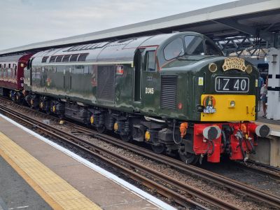 Class 40 1Co-Co1 diesel-electric D345 (40 145) stands at the head of the Pathfinder Golden Anniversary railtour train, on 10th June 2023. (Peter Latham) A large heritage diesel locomotive (BR Class 40) with railtour headboards, beautifully restored into mid-1960s green livery, standing at a station.
