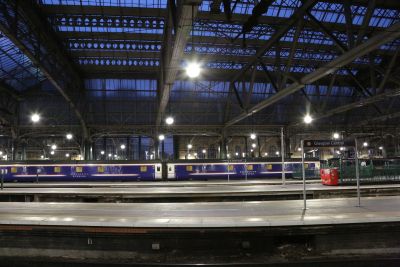 The overnight sleeper for Euston before departure from Glasgow Central on 30 June 2017. – Stephen Bigley Interior view across the deserted platforms of a major city station, late on a summer evening. Dominant above, the overall roof is supported by an intricate mesh of iron girders; while On the furthest platform, a sleeper train awaits its turn to head south.