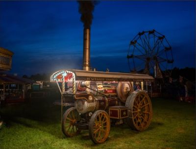 1914 Fowler 10NHP B6 Showmans Road Locomotive 'Carry On' (works no 14425, reg. no. DP 4418), in livery of 'McGivern's Gigantic Pleasure Fairs', hard at work generating power for a vintage fairground ride. – Simon Colbeck Night-time view of a brightly-coloured traction engine on a vintage fairground, stationary, but steaming at full power. The lights on the showmans road locomotive use the electricity it is generating for the rides.