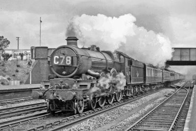 GWR 4-6-0 No. 7018 'Drysllwyn Castle' heading through Newbury with the Down 11:30 Paddington-Penzance express – sometime in the 1960s (David Canning) A large Great Western Railway steam locomotive hauling an express passenger train at speed through a provincial station.