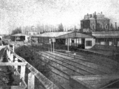 Slough Station in the 1850's: two simple wooden train sheds straddle the same running lines on the far side of the railway.