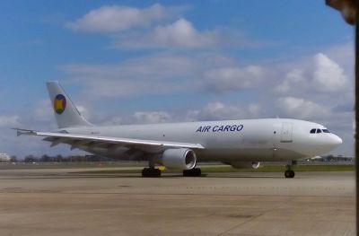 A twin-engine jet airliner designed for airfreight (ie no windows) taxis across the hardstanding at an international airport.