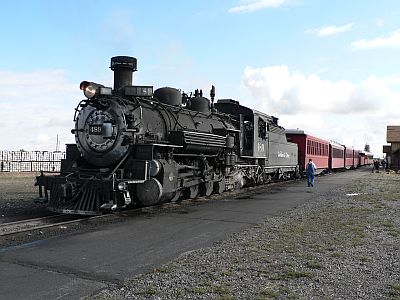 A restored American 2-8-2 tender steam locomotive at the head of a rake of vintage carriages.