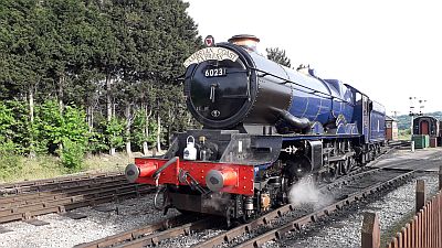 A large GWR express passenger steam locomotive (King Edward I) runs light engine at a rural heritage railway.