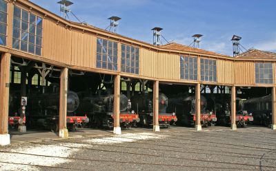 French steam locomotives peering out of a roundhouse engine shed