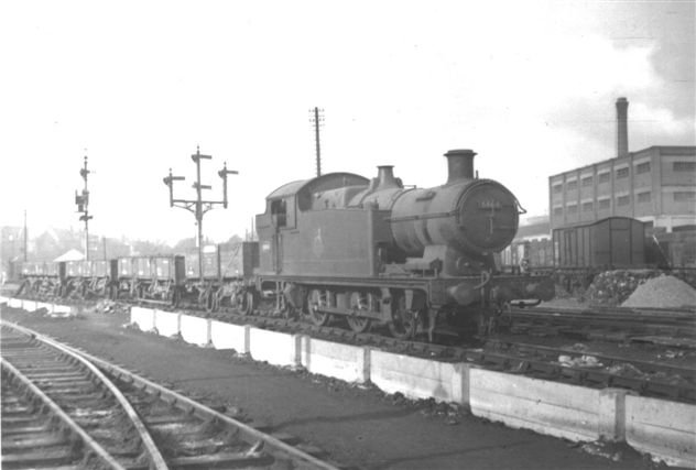 October 1955 picture of a busy railway scene featuring an 0-6-2T steam locomotive amongst many short wheelbase vans and open wagons.
