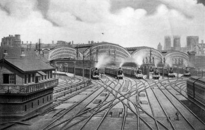View circa 1910: complicated pointwork leads to the platforms at which no less than seven passenger trains are waiting beneath the four arched spans of the grand overall roof of York Station.